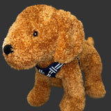 A plush golden-brown dog toy wearing a navy blue harness with reflective stripes,