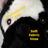 Close-up of a plush animal face in black and white fabric, showing embroidered eyes and soft fabric nose, with yellow text overlays reading 'Embroidered Eyes' and 'Soft Fabric Nose'.